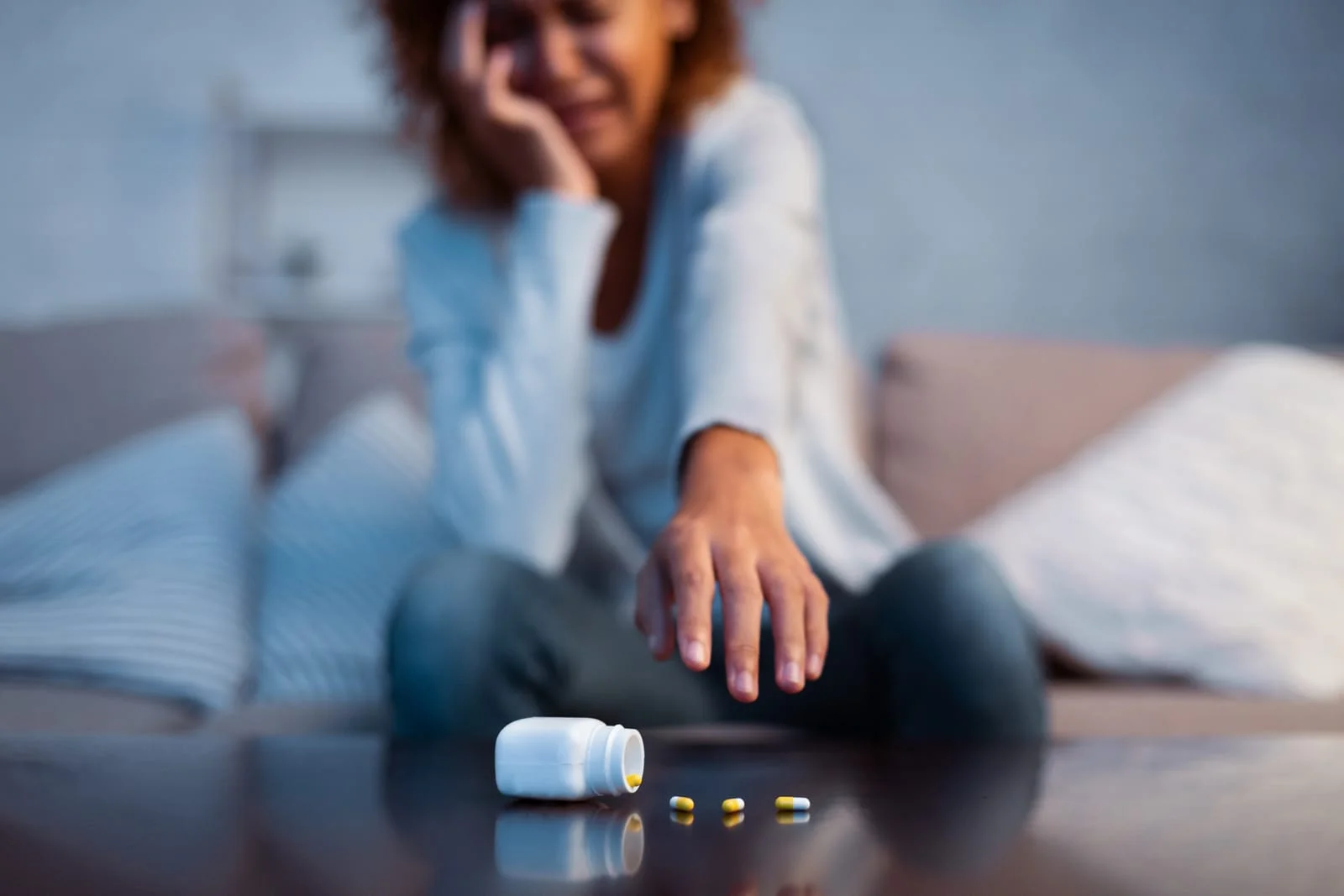 Depressed woman catching antidepressant pills and crying